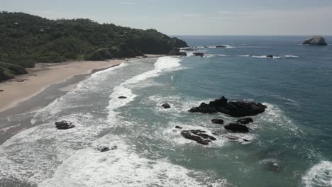 sand beach and rugged offshore rocks on sea shore blue ocean coast