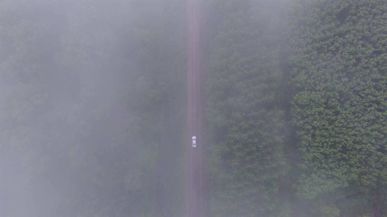 Experience the unique top-down perspective of a moving car on a dirt road, with clouds overhead and the landscape unfolding as the vehicle travels forward. A dynamic shot capturing motion and scenery