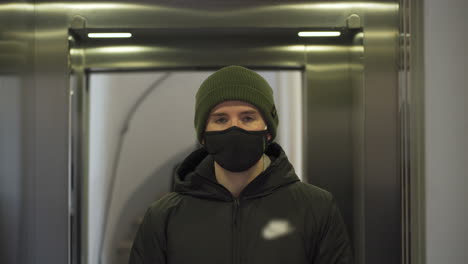 young man with black mask standing in an elevator in times of corona virus.