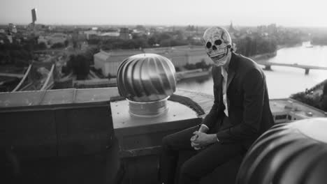 person in skull mask on rooftop overlooking city