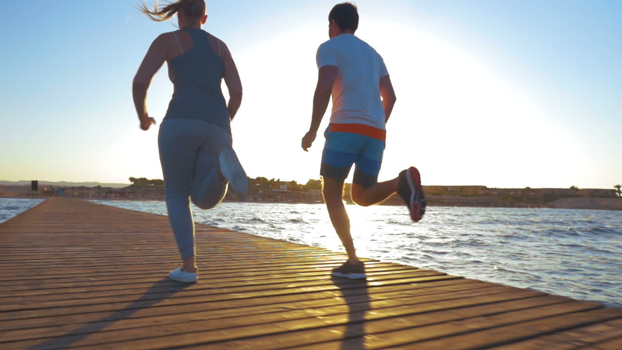 jóvenes corriendo en el muelle al atardecer