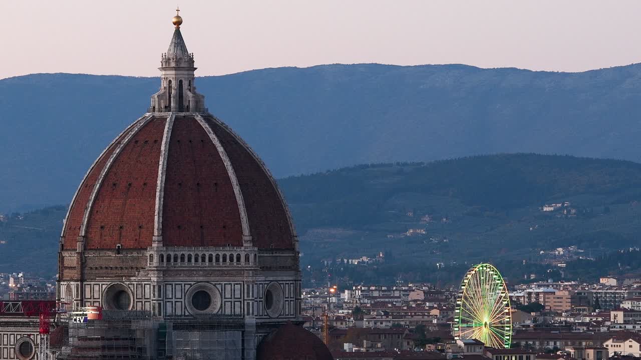 피렌체의 산타 마리아 델 피오레 대성당은 미란젤로 광장에서 볼 수 있으며, 왼쪽 배경에는 조명된 페리스 이 있습니다.