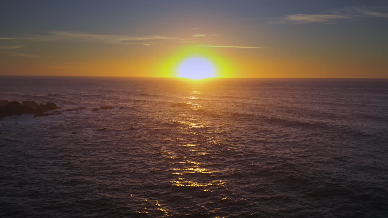 Arcing drone shot of sunset over the sea.