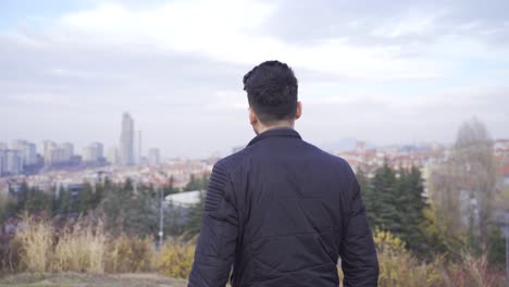 un joven triste y solitario mirando pensativo a la ciudad.