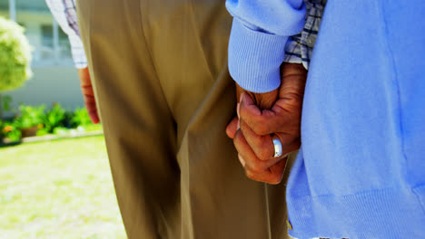 Mid-section-of-active-senior-couple-walking-hand-in-hand-in-the-garden-of-nursing-home-4k