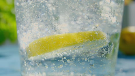 una rebanada de cal flotando en un vaso de agua carbonatada gaseosa