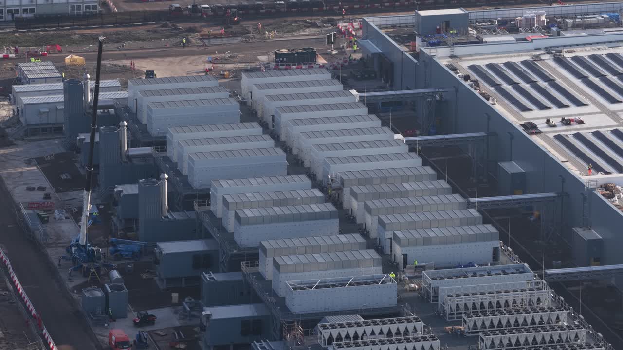 Ovenfra-billede viser konstruktionen og udvidelsen af et stort, moderne datacenter, fremhæver installationen af køleenheder og servermoduler på industribygningen.