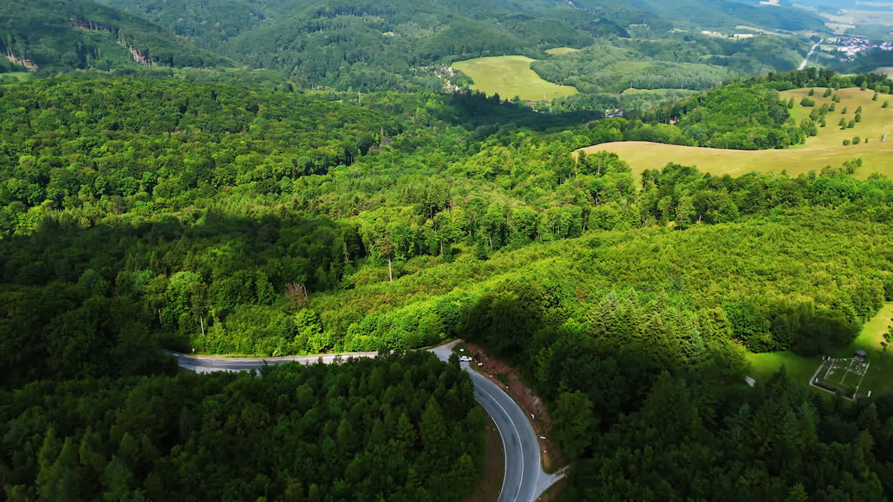 Footage above the vast green forests covering the mountainous area. Wavy road crosses the picturesque wooded area