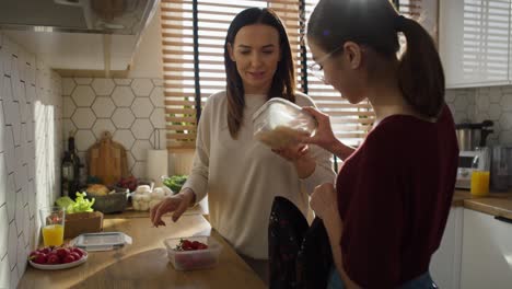 Caucasian-mother-giving-a-lunch-box-to-daughter-to-school