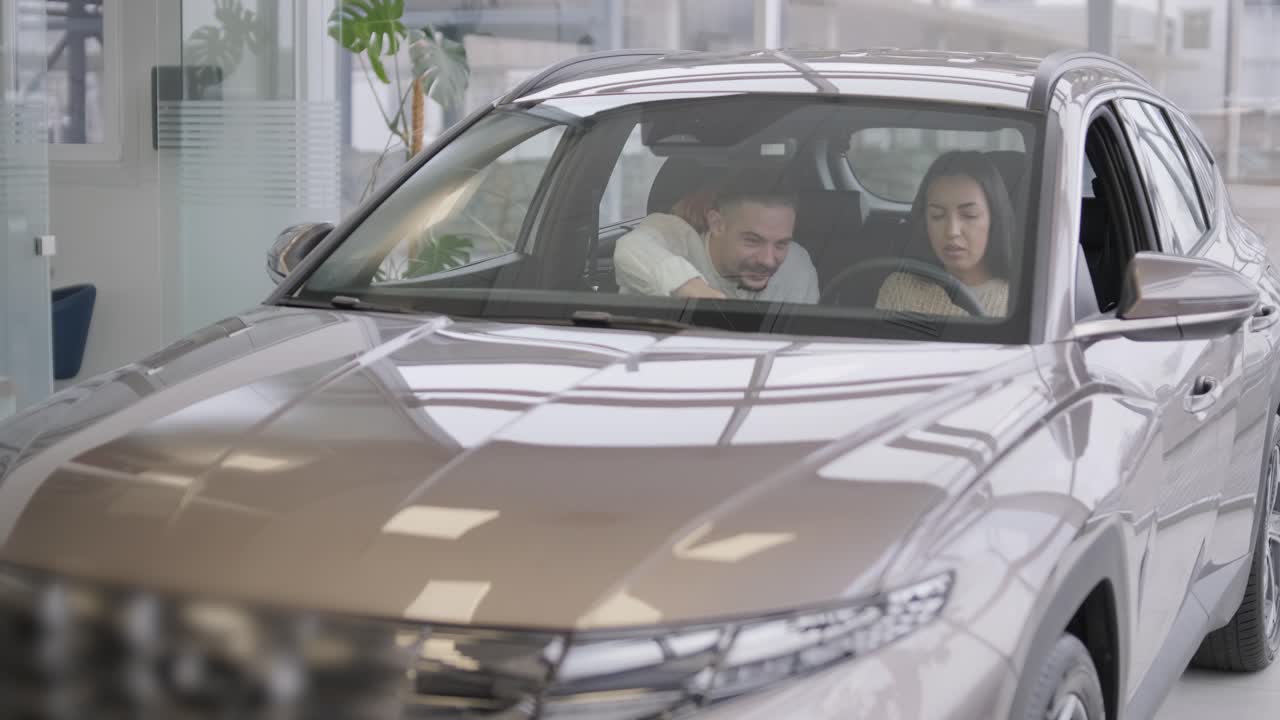 una hermosa pareja de jóvenes en la sala de exposición de automóviles eligiendo un coche nuevo para comprar.