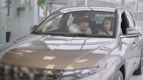 beautiful young couple at car showroom choosing a new car to buy.