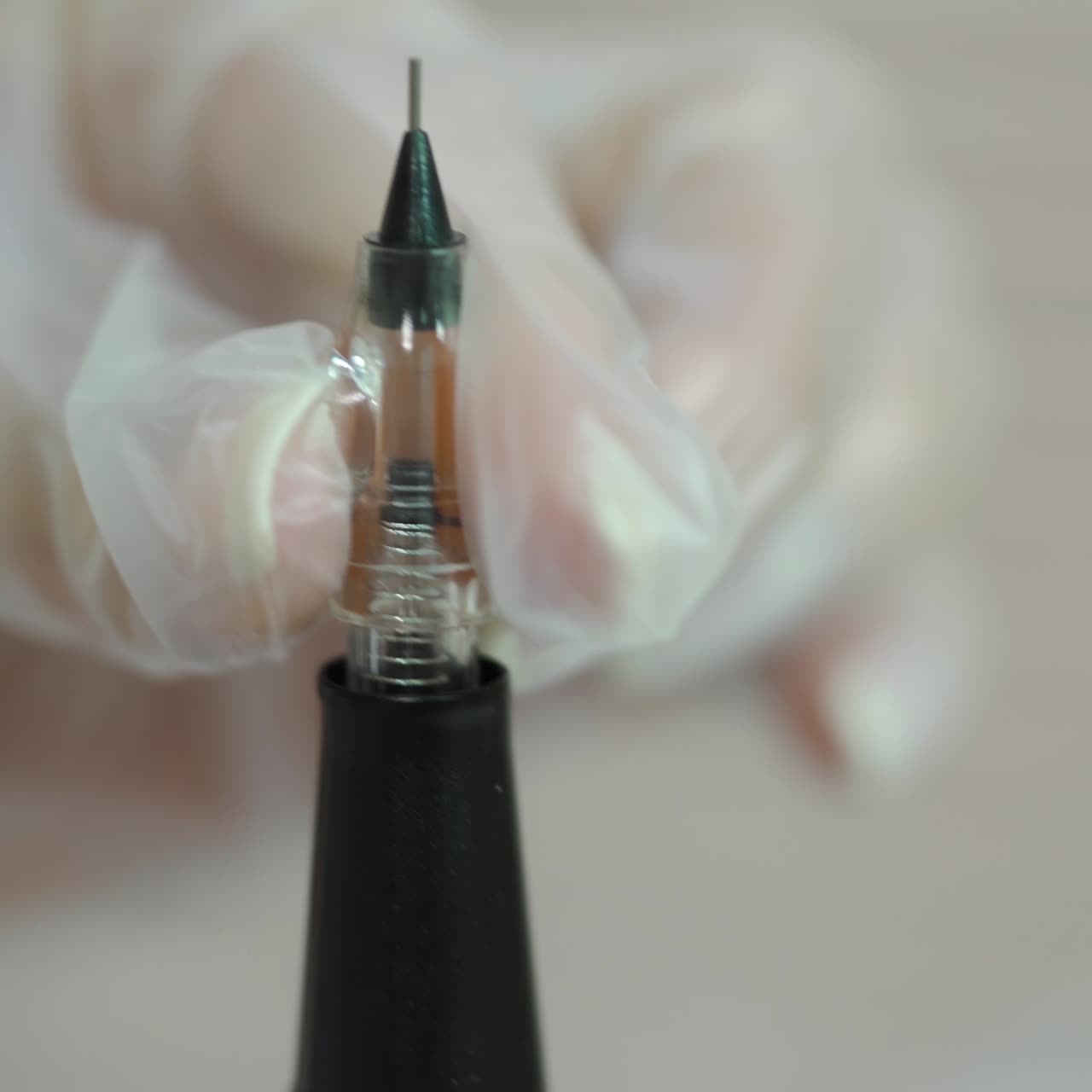 cosmetologist is holding a brush with a needle for permanent makeup of eye. Close-up. Modern methods of cosmetology. Blurred background