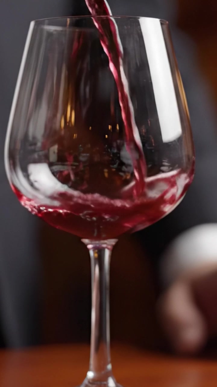 Trasformazione accattivante: Dal bicchiere vuoto al versamento di un ricco vino rosso, rivelato in inquadrature ipnotizzanti della maestria di un sommelier