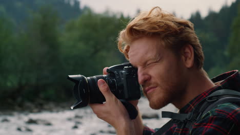 male photographer taking pictures of nature. redhead man using photo camera