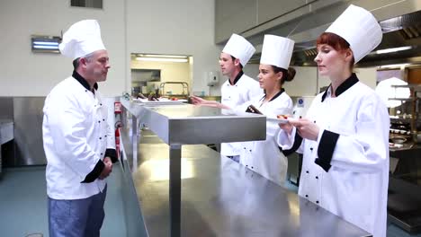 jefe de cocina inspeccionando los postres de sus estudiantes