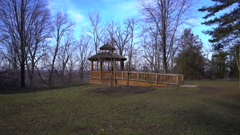 gazebo with leaves blowing during start and end of winter 4k - outdoor wooden gazebo romantic with no people in nature forest opening