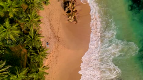 erial-overview-of-huge-waves-crashing-into-the-shore-and-rocks-at-a-beach-in-Sri-Lanka,-overview-shot-showing-the-dynamic-coastline-of-the-turquoise-waters-of-Tangalle,-Sri-Lanka