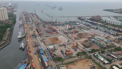 boats containers trucks and cranes in the batavia ancol marina harbor north jakarta indonesia track backwards