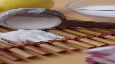 baking soda, lemon, and a wooden spoon on a bamboo mat