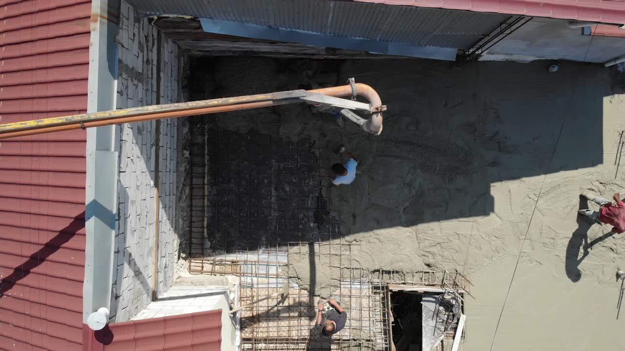 Overhead aerial drone shot of workers pouring concrete in summer time