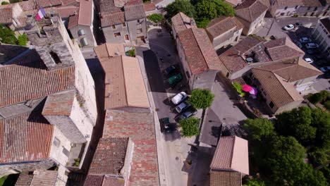 Vintage-Morgan-in-Picturesque-Village:-Aerial-View-of-Classic-Car-Driving-past-French-Flag-and-Church-Bell-Tower