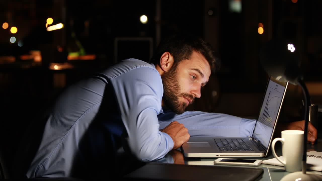 Tired businessman using laptop at night