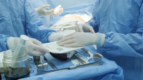 the surgeon prepares a sterile silicone breast implant for breast augmentation surgery