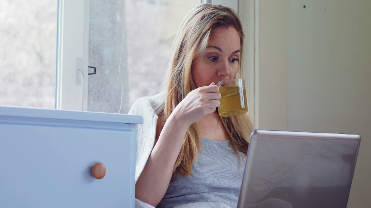 mujer usando computadora portátil mientras toma té verde 4k