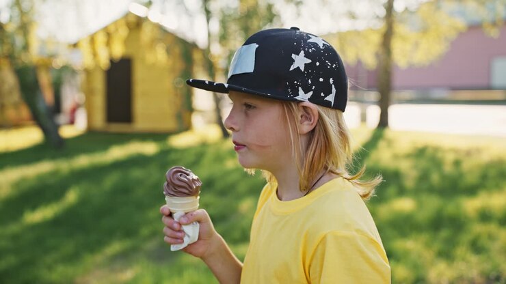 Ragazzo che mangia gelato al cioccolato al parco