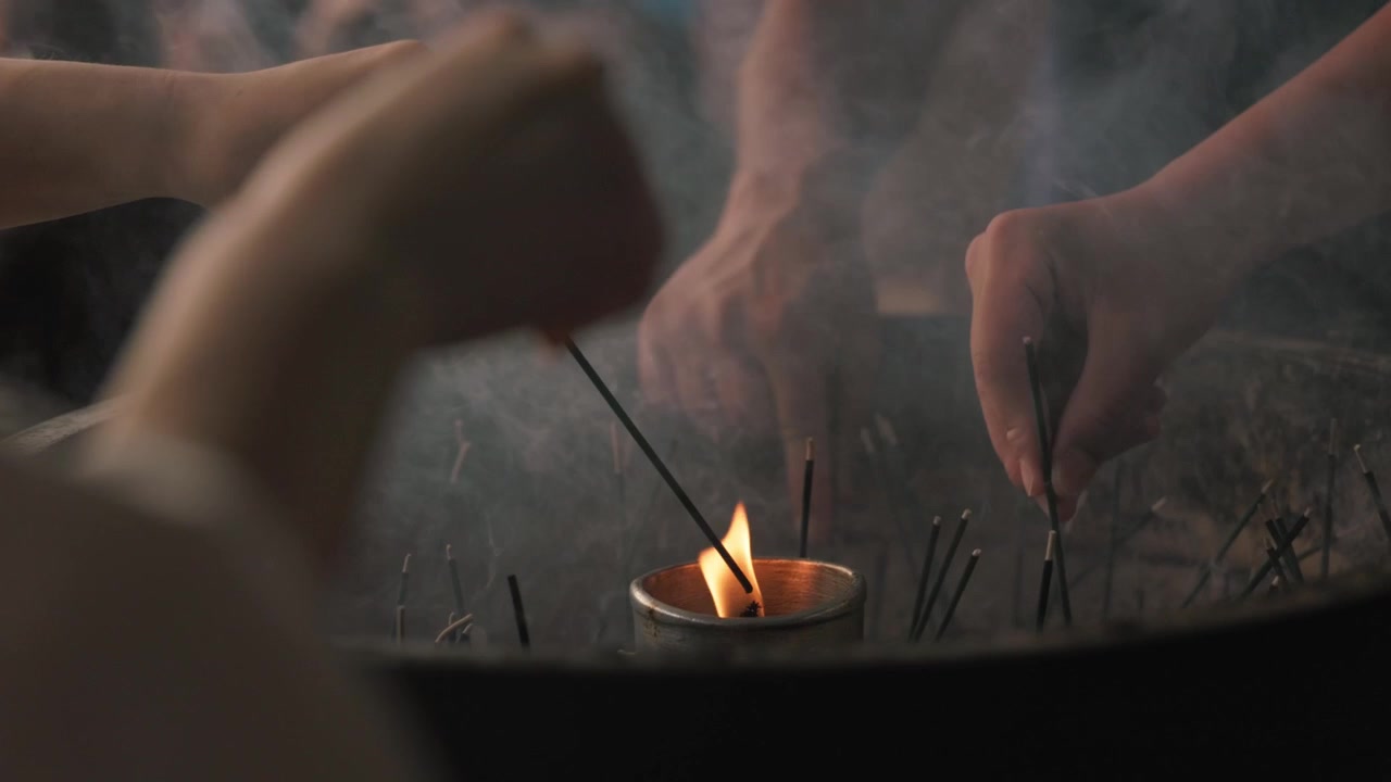Manos encendiendo varitas de incienso en un templo o santuario japonés en Japón - primer plano.