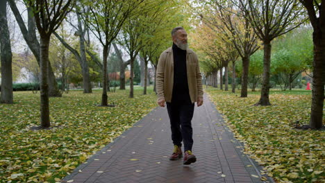 hombre mayor caminando en el parque de otoño