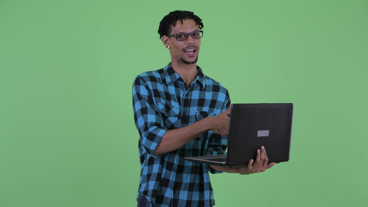 joven feliz y guapo hombre hipster africano usando una computadora portátil