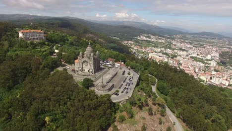 aerial dolly forwards towards viana do castelo church in portugal on forested hilltop