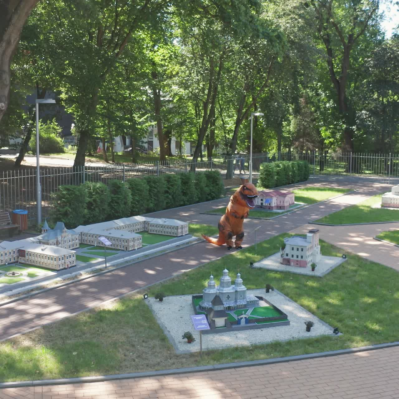 City park walking happy dragon costume. Street walking by funny dragon suit