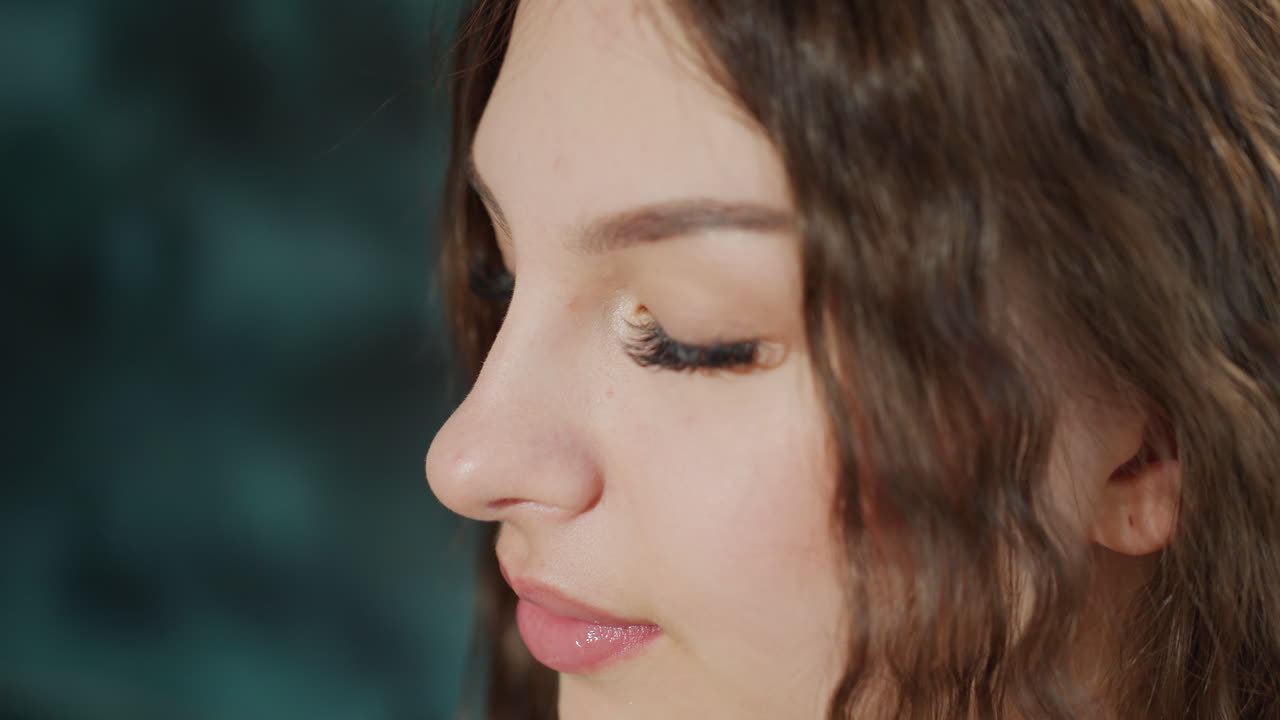 Closeup Profile Caucasian Woman Applying Eyeshadow With Professional Brush, Makeup Artist Creating Soft Glam, Focused Expression, Long Lashes, Curly Brown Hair, Warm Studio Lighting, Precision