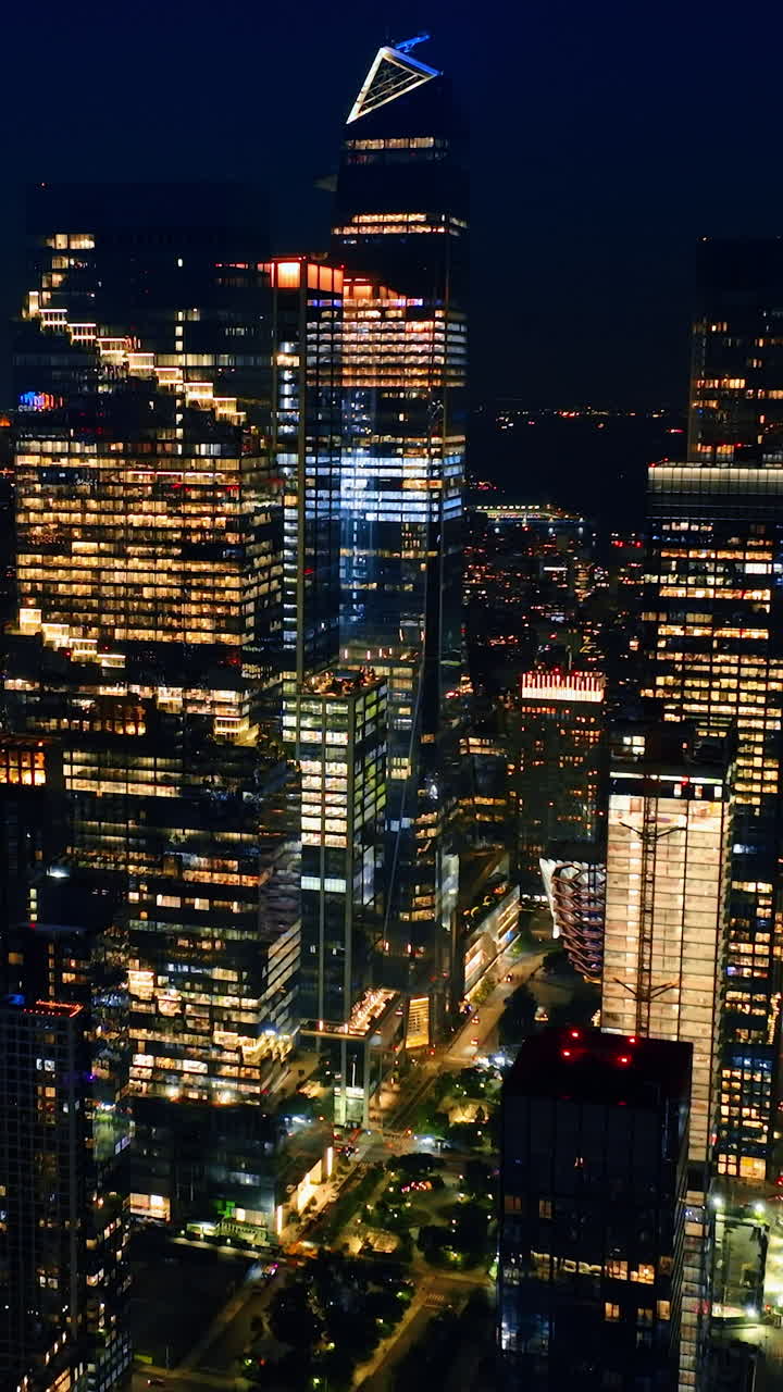 Rising to the tops of magnificent skyscrapers. Amazing New York full of lights at night. Top view panorama. Vertical video