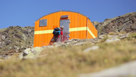 un excursionista abriendo una cabaña de metal en una montaña