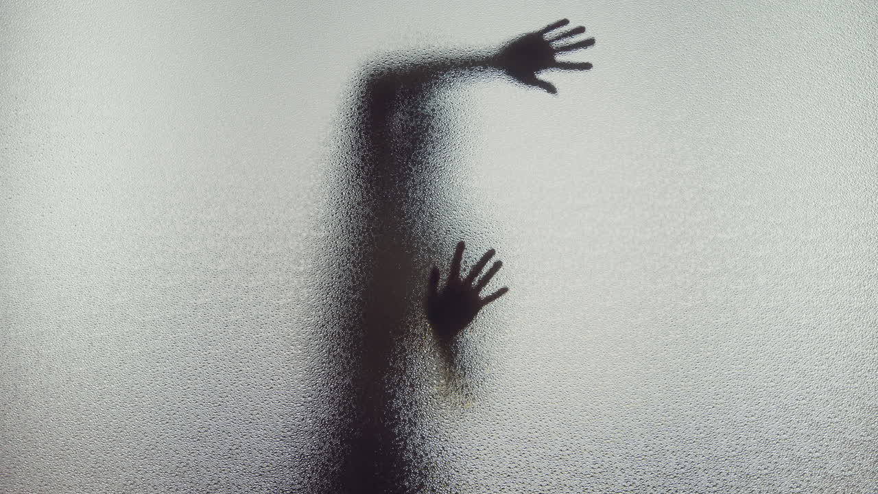 A female silhouette behind the frosted window dances slowly