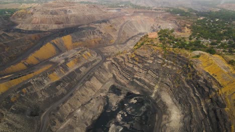 aerial view of dhanbad’s coal fields, showcasing the expanse of mines and the smoke-filled industrial air.