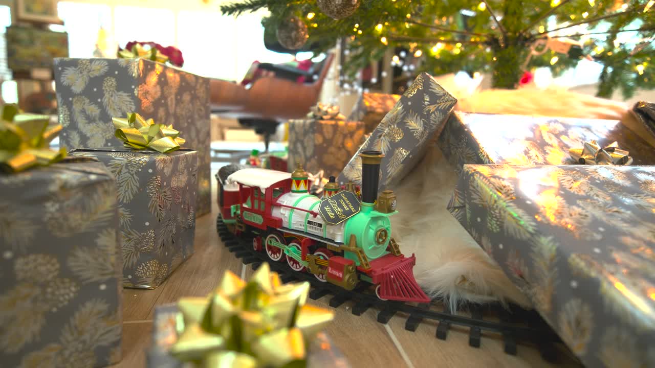 "Captivating stock footage: Glide beneath a festive Christmas tree, presents galore, showcasing a model train, spreading joy in a delightful forward sliding shot