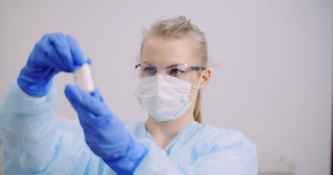 científica femenina sosteniendo tubos y matraz con líquido en las manos 4