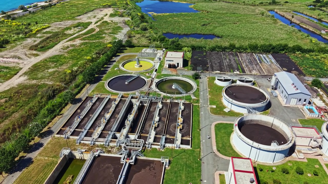 Water treatment facility in a rural area near a river with multiple basins and tanks for processing wastewater during the day