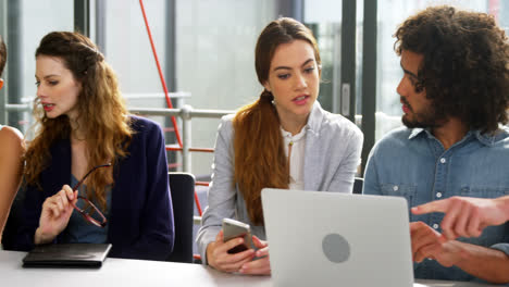 Business-executives-discussing-over-laptop-in-meeting