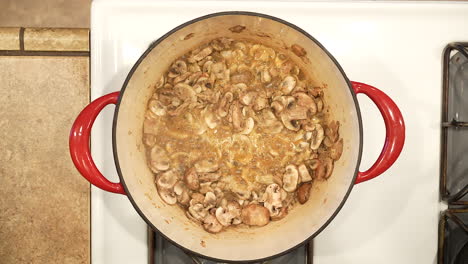 sauteing organic cremini mushrooms in a pot on the stove for a delicious soup - overhead view wild rice series