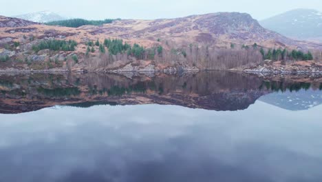 Sensational-aerial-in-lake-Loch-Lochy,-calm-water-reflection,-rising-above-hills