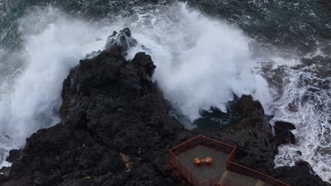 dramatic ocean waves crashing against dark volcanic rocks