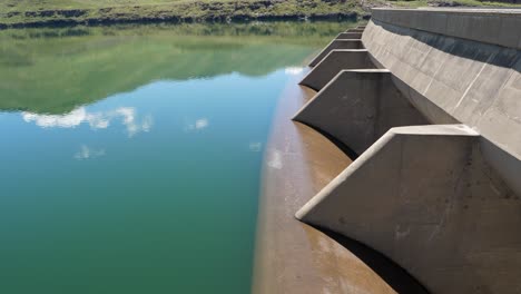 high water trickles calmly over flood gates atop hydro electric dam