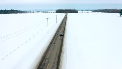 Drohne,-Die-Einem-Auto-Folgt,-Das-Im-Winter-Auf-Einer-Landstraße-Fährt