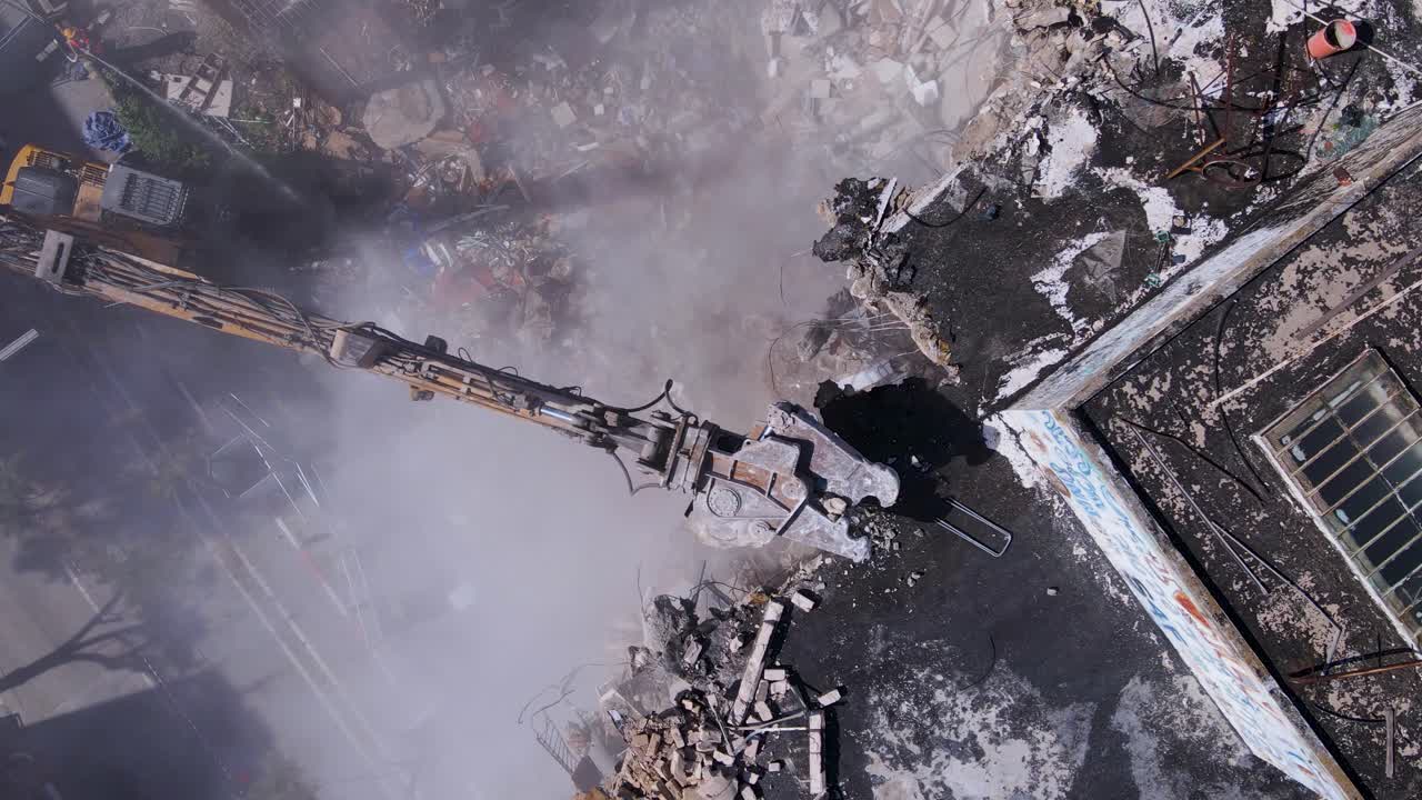 demolición de un edificio antiguo por una excavadora con accesorio de trituradora