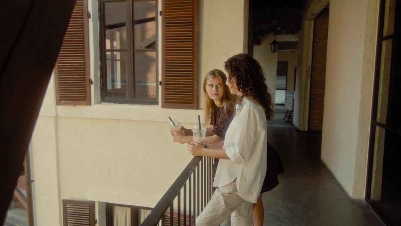 Two Women Enjoying Drinks on a Balcony